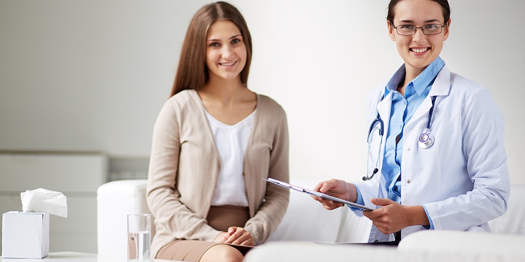 Female psychiatrist looking at camera with her patient near by